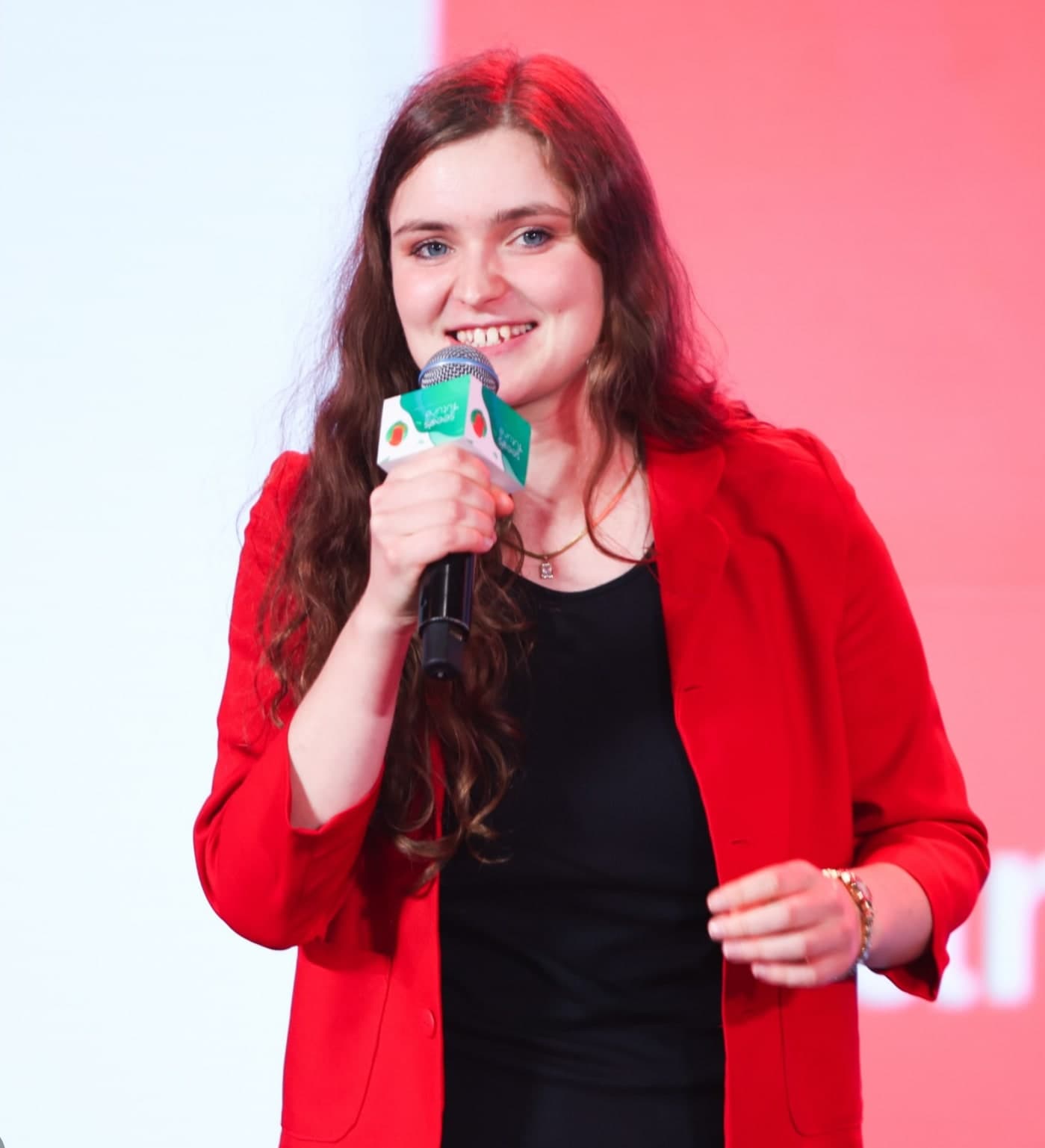 Sarah Mayrhofer speaking on stage with a microphone